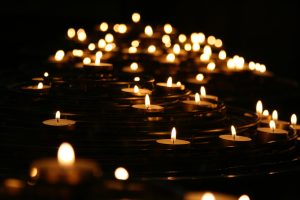 Many tea lights lit in a dark room.
