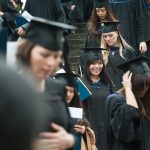 A throng of students in graduation regalia walking down the stairs to the Chan Centre for convocation.