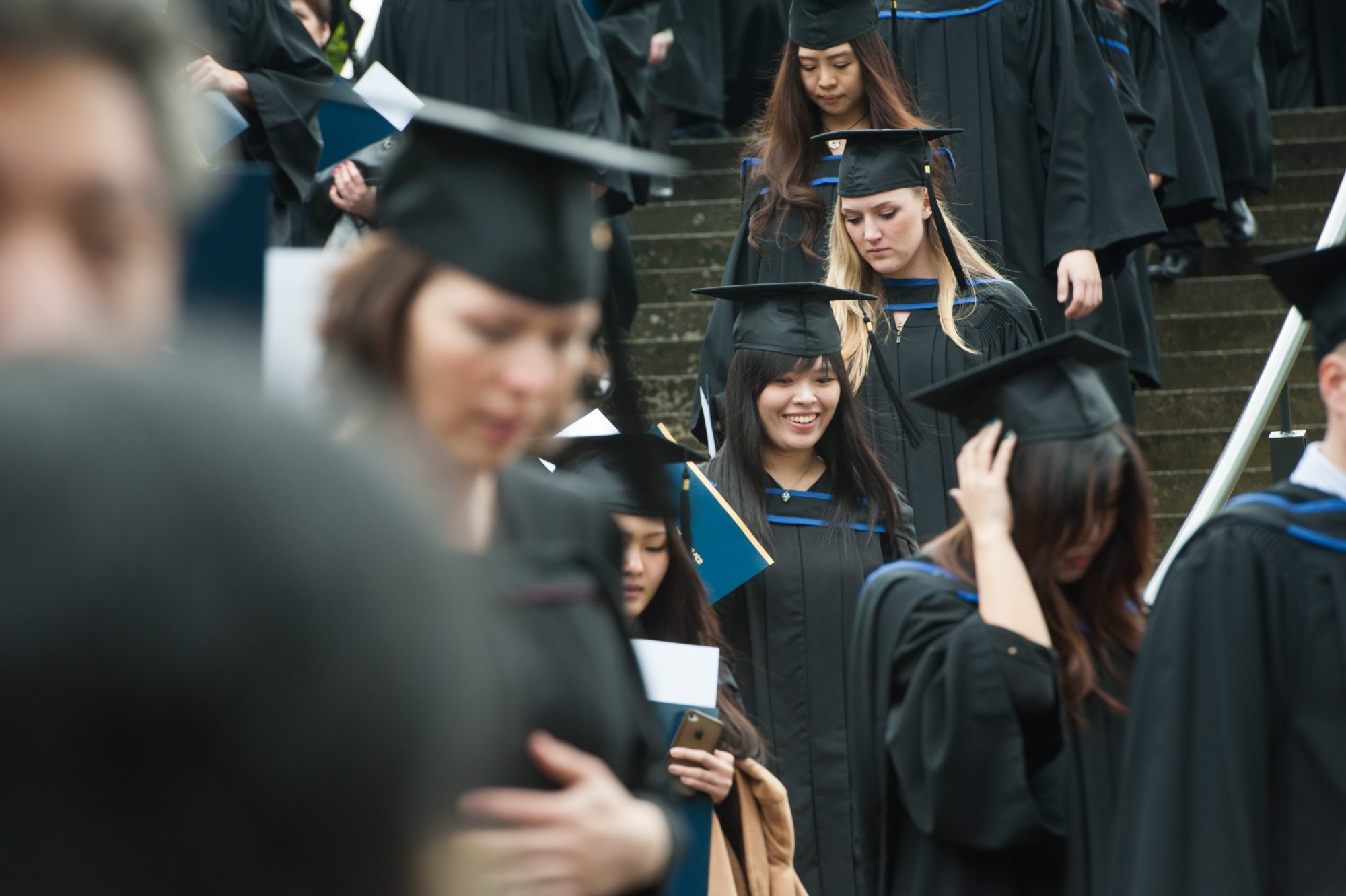 A throng of students in graduation regalia walking down the stairs to the Chan Centre for convocation.