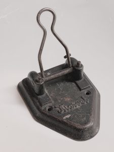 Vintage paper punch with a rounded triangle shape and a loop-like lever, made out of metal.