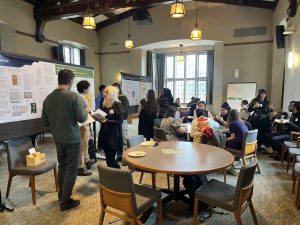 A group of iSchool students at Research Day 2025 discussing posters and eating food.